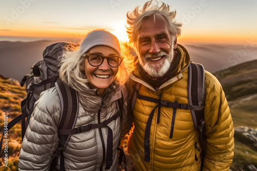 Old hiking couple with grey hear enjoy the beautiful sunset in the mountain during a hiking tour and making a happy smiling self portrait selfie, generative ai 