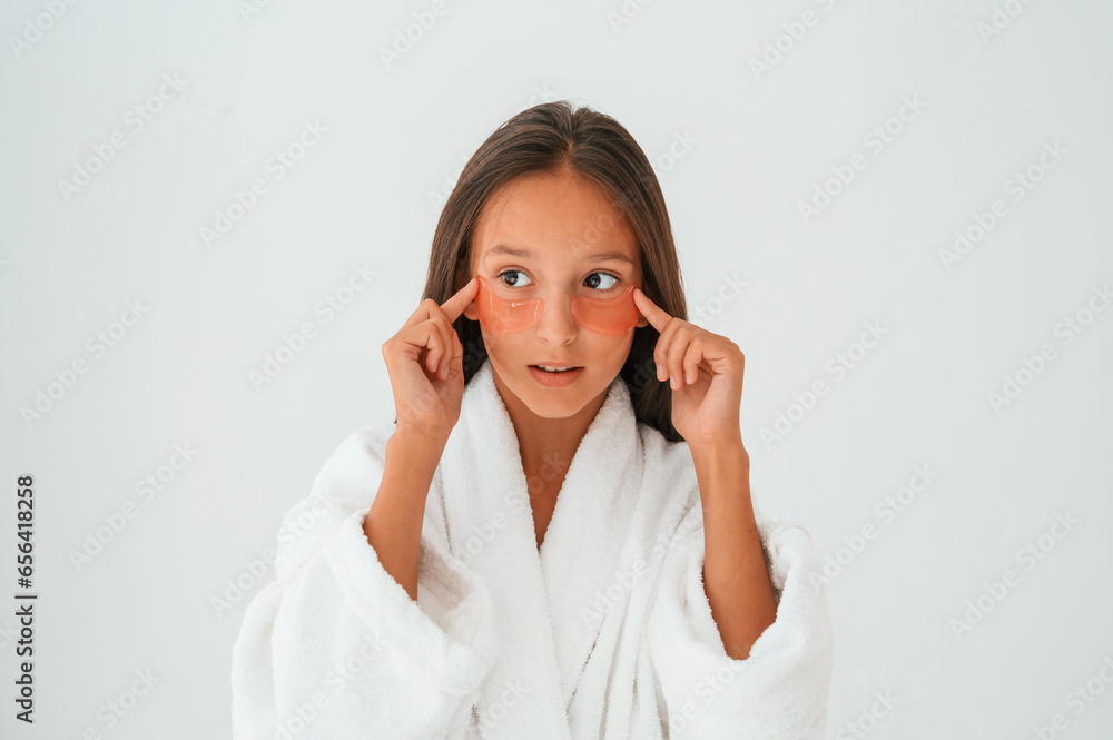 Trying eye patches. Conception of beauty and self care. Young girl is in the studio Trying eye patches. Conception of beauty and self care. Young girl is in the studio
