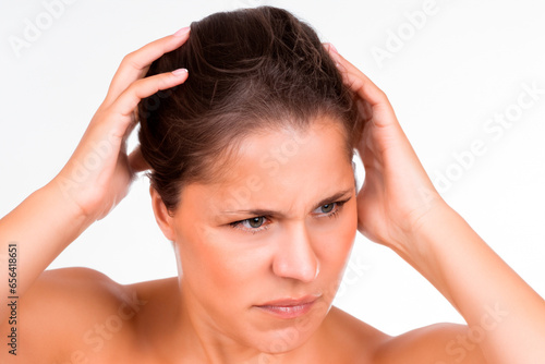 Portrait of a woman with a severe headache holding her head and looking into the distance