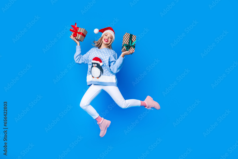 Full body cadre of jumping with two gift boxes girl invite brochure shopping mall new year atmosphere isolated on blue color background Full body cadre of jumping with two gift boxes girl invite brochure shopping mall new year atmosphere isolated on blue color background