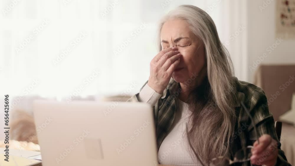 Portrait of tired overworked gray haired senior woman freelancer with eyes hurt massaging having bad poor vision after hard day working on laptop computer typing and browsing at home workplace Portrait of tired overworked gray haired senior woman freelancer with eyes hurt massaging having bad poor vision after hard day working on laptop computer typing and browsing at home workplace