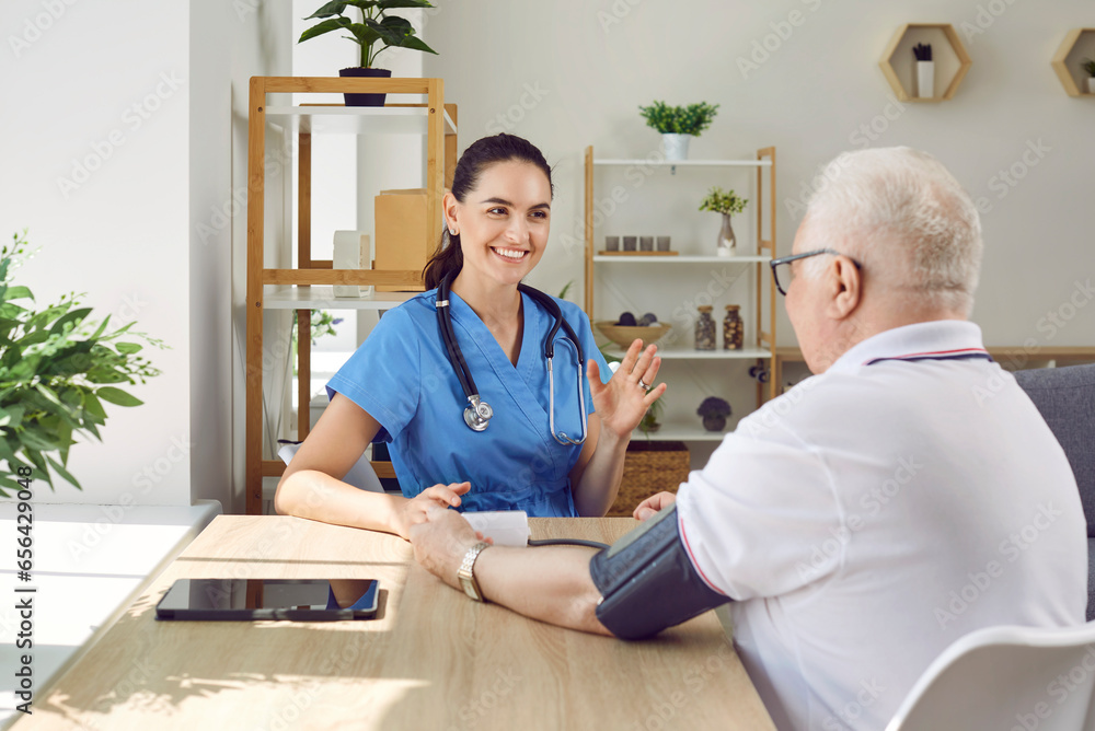 Obraz premium Nurse or caregiver woman measuring arterial blood pressure of elderly patient man with hypertension. Senior man on checkup appointment sitting in modern hospital. Treatment and care of old people.