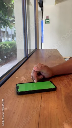 Man's hand scrolling on a phone green screen 