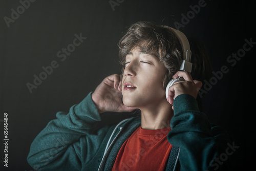 Boy listening to music with his headphones with a relaxed face.