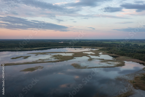 Aerial view on Braslav lake Snudy, Belarus. Summer sunset on lake Snudy, small islands on lake of dry reed. The sky is reflected from the surface of the lake water.