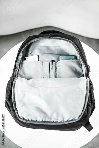 An unbuttoned black backpack with a large compartment, a phone and a pen