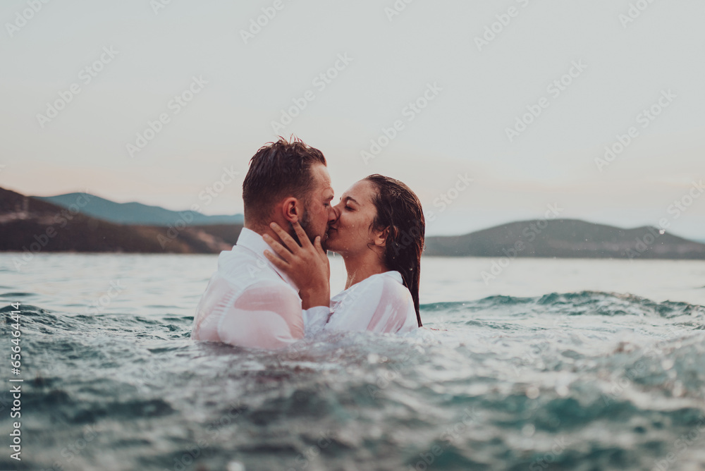 A romantic young couple sharing a passionate kiss amidst the serene beauty of the ocean at sunset. A romantic young couple sharing a passionate kiss amidst the serene beauty of the ocean at sunset.