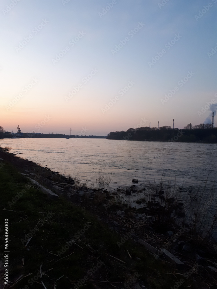 Fluss (Rhein) bei Sonnenaufgang mit einer Raffinerie an der Küste Fluss (Rhein) bei Sonnenaufgang mit einer Raffinerie an der Küste