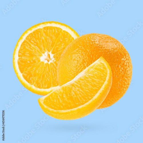 Juicy oranges closeup fly as art composition. Whole  half and quarter piece fruits on pastel blue background with shadow. Summer fruits for advertising  design  label product.
