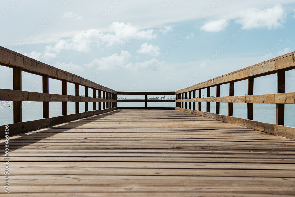 perspective of a wooden bridge in a coast  with a cloudy sky from puerto rico 