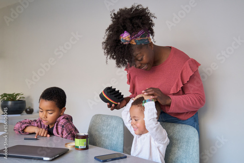 Toddler son playing while his african mother tries to style his hair using an afro curl or twists sponge. photo