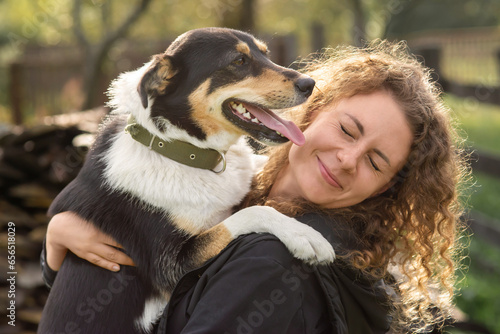 A dog licks a woman's face outdoor.