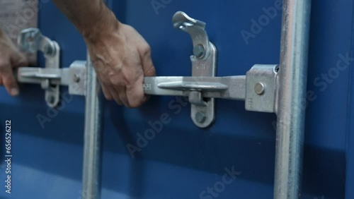 Close up view on man hands is opening the lock of large shipping container doors