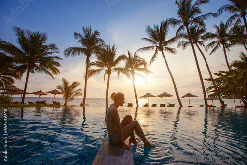 spa, silhouette of woman relaxing near swimming pool on the beach at sunset in luxury hotel