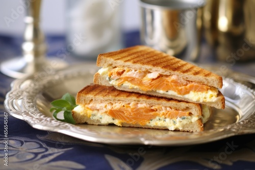a salmon and cream cheese toasted sandwich on a silver tray