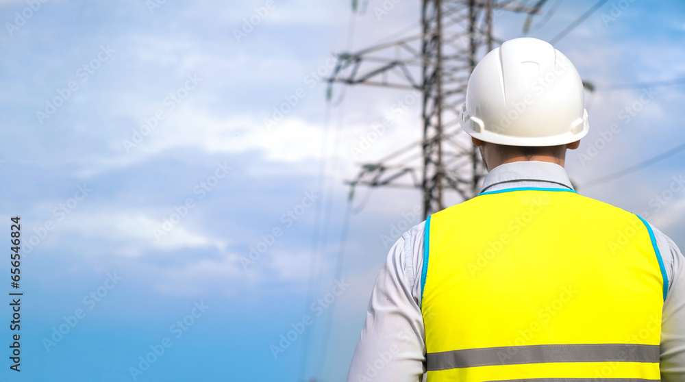 male engineer, power engineer in a helmet checks a power line using a tablet online. Electrician outdoors. High voltage electrical lines at sunset. Electricity distribution and supply male engineer, power engineer in a helmet checks a power line using a tablet online. Electrician outdoors. High voltage electrical lines at sunset. Electricity distribution and supply