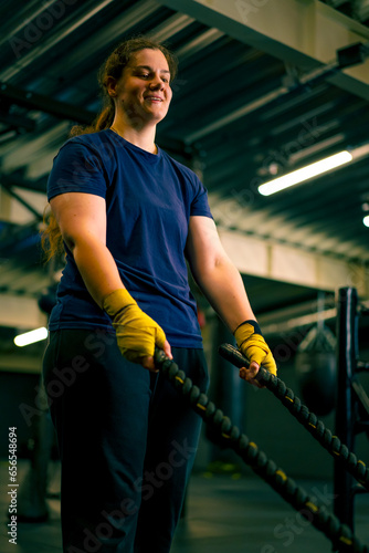concentrated female athlete doing exercises with ropes in gym training muscles sport concept