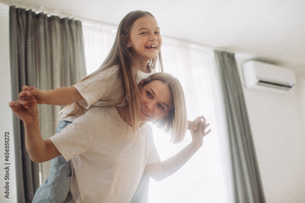 Happy mother piggybacking adorable little daughter at home.. Happy mother piggybacking adorable little daughter at home..