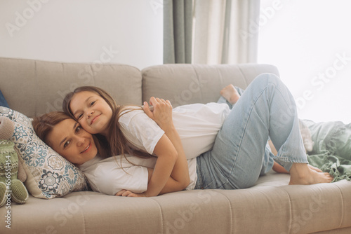 Cute little girl hug cuddle excited young mum show love and affection, smiling mother and funny small daughter have fun at home embrace sharing close tender moment together.