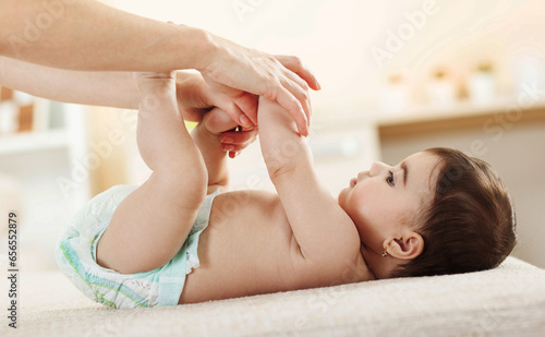 Delicate moments of motherhood as a caring mother gently guides her baby girl through leg exercises.