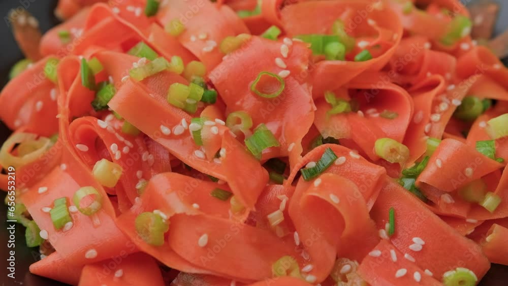 Asian carrot salad with spices and herbs in black bowl. Rotating video Asian carrot salad with spices and herbs in black bowl. Rotating video