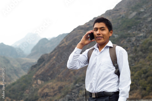 Una foto de una chico campesino alumno caucásico usando un smartphone durante la publicidad en un parque, Hombre nativo quechua con celular, estilo de vida,Comunicación photo