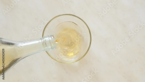 apple cider vinegar is poured from the bottle into a glass bowl