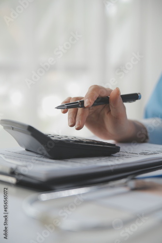 Doctor or physician using calculator and work on laptop computer with medical stethoscope on the desk at clinic or hospital. Medical healthcare costs ,fees and revenue concept.