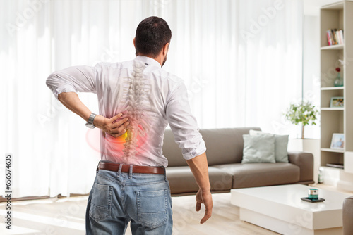 Rear view shot of a man with painful back in a living room