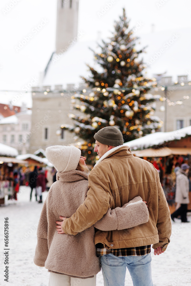 couple hugging at christmas market on town hall square in tallinn, estonia