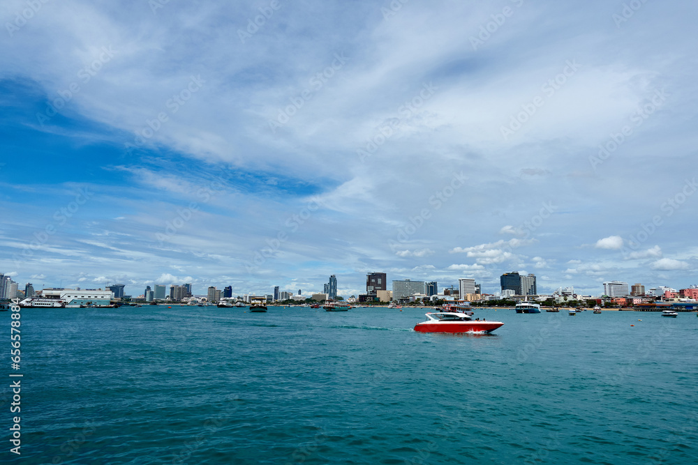 Landscape of Pattaya Bay and Pattaya city during the daytime with speedboat tour boats moored in the bay.