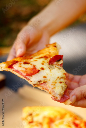 the girl holds a piece of pizza in her hands, fast food