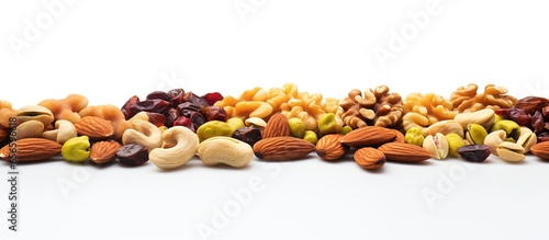 Variety of nuts and dried fruits including almonds cashews pistachios and raisins on a white background with copyspace for text