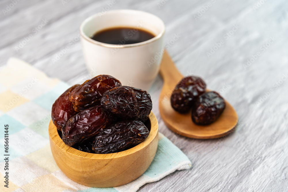 Dried dates fruit in wooden bowl with a cup of coffee. Dried dates fruit in wooden bowl with a cup of coffee.