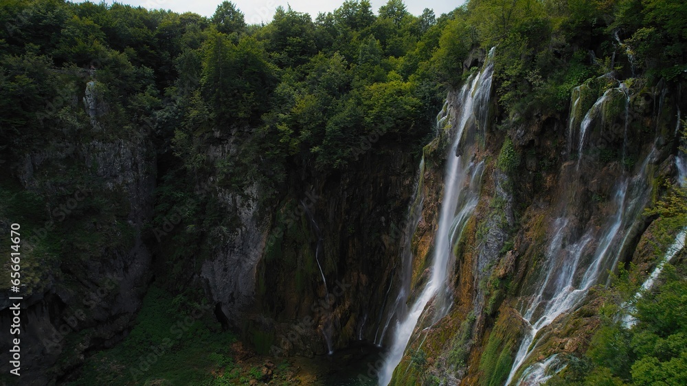 Amazing waterfall falling from a high cliff in lush green forest. Mountain cascade with clear water. Amazing waterfall falling from a high cliff in lush green forest. Mountain cascade with clear water.