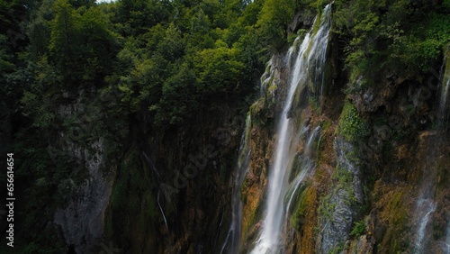 Amazing waterfall falling from a high cliff in lush green forest. Mountain cascade with clear water.