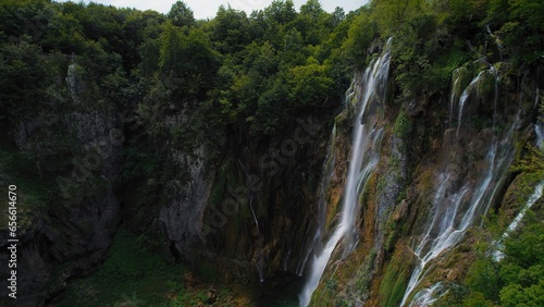 Amazing waterfall falling from a high cliff in lush green forest. Mountain cascade with clear water.
