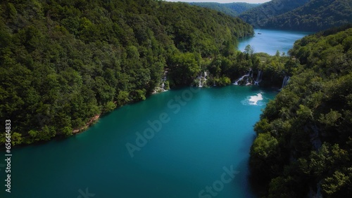 Turquoise water of lake in mountain forest with pine trees. Aerial view of blue reservoir and green woodland in summer.