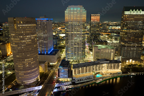 Aerial view of downtown district of Tampa city in Florida, USA. Brightly illuminated high skyscraper buildings, pedestrian riverwalk and moving traffic in modern american midtown