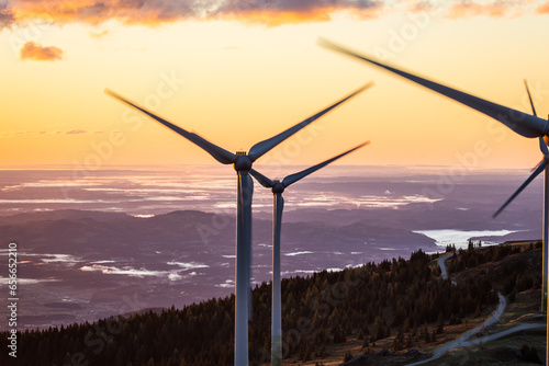 Turning wind power plant during sunrise on a mountain in Austria photo