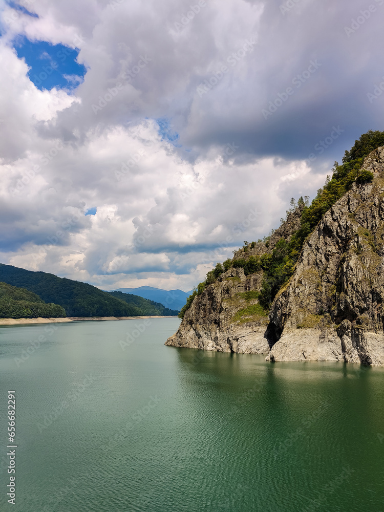 Scenic view of the reservoir of the Vidraru dam in Romania. A high rocky mountain on the artificially created Lake Vidraru. Copy space. Selective focus.