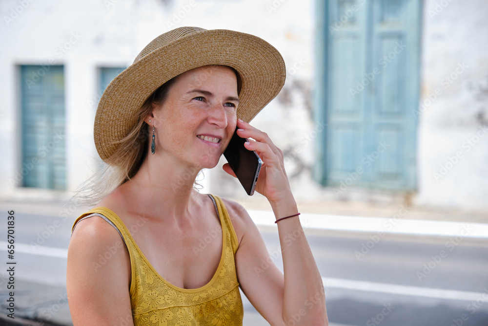 Smiling female talking on smartphone on summer street