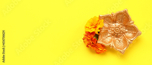 Diya lamp and marigold flowers on yellow background with space for text. Celebration of Divaly (Indian Festival of Lights) photo