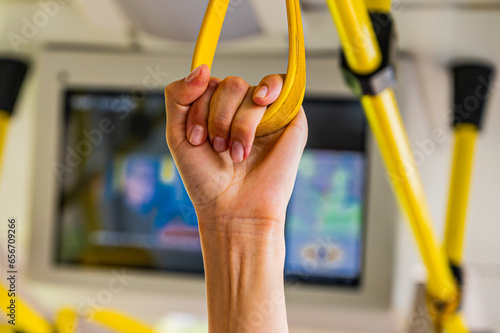 people holding onto a handle on a train