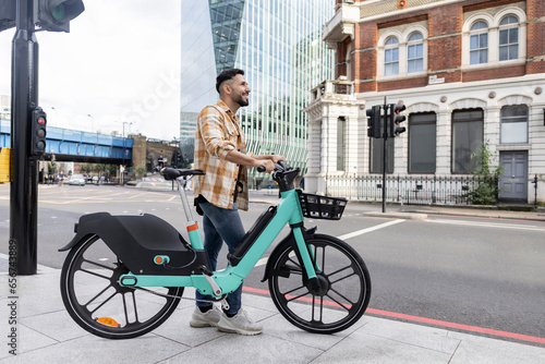 attractive hispanic man with his rented e-bike touring the city photo