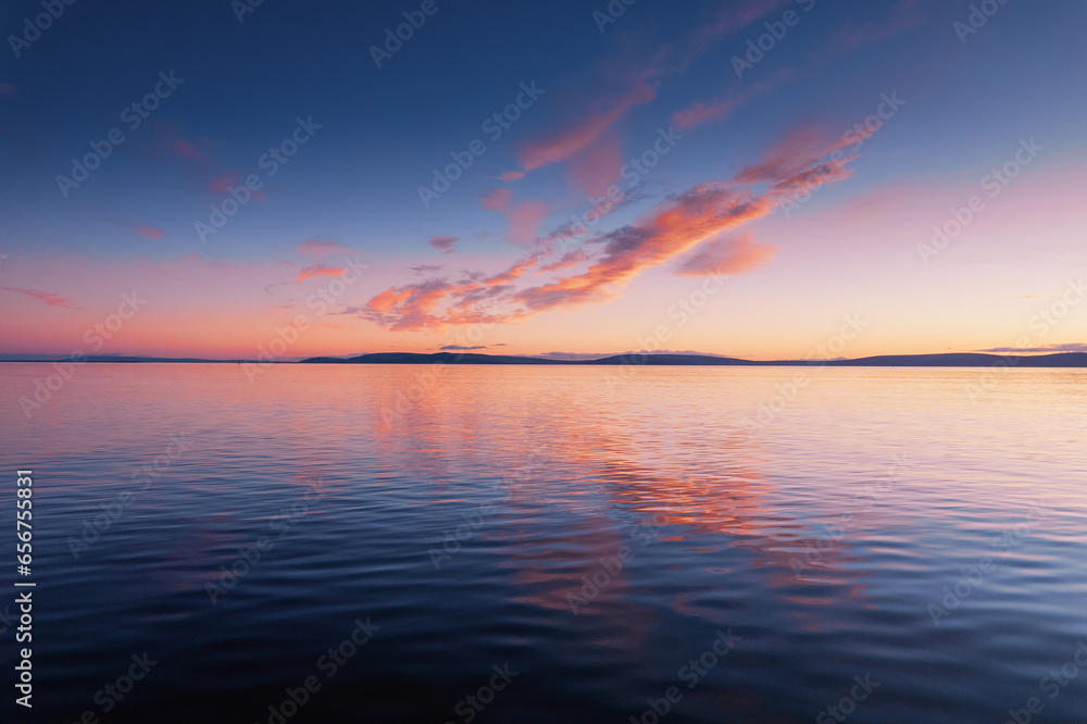 Blue cloudy sky over Burren mountains and reflection in dark water of Galway bay, Ireland. Blue hour nature scene. Nobody. Aerial view. - obrazy, fototapety, plakaty 