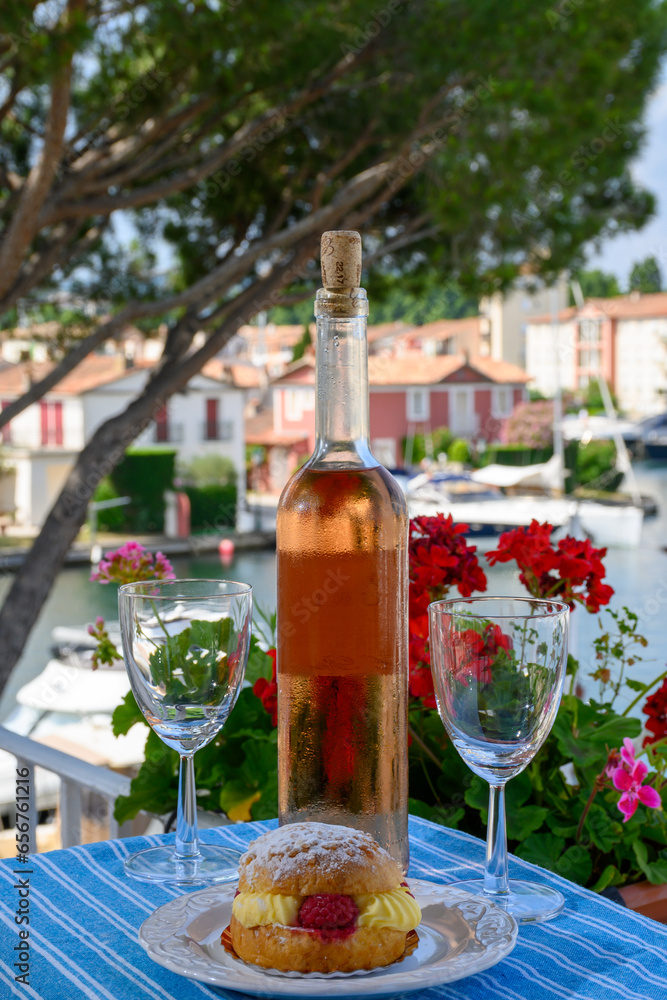Wine and cake of French Riviera, glasses of cold rose Cote de Provence wine and Tarte Tropezienne cake in yacht harbour of Port Grimaud, summer vacation  in Provence, France.