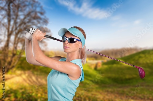 Young sporty female golfer player hitting ball