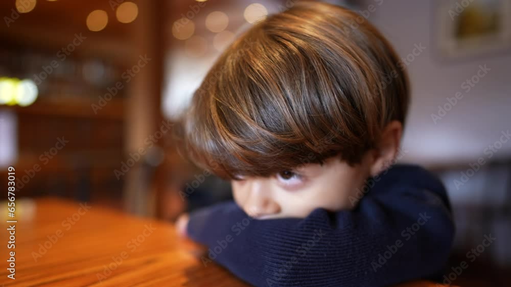 Pensive little boy leaning on table with deep introspective emotion. Close-up face of a thoughtful caucasian child Pensive little boy leaning on table with deep introspective emotion. Close-up face of a thoughtful caucasian child