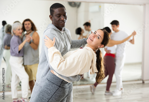Confident couple of dancers, engaged in a dance studio in a group class, enjoys a partner dance
